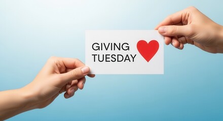 Hands holding a card with the text Giving Tuesday and a red heart symbol. Charity, donation, and philanthropy concept on a blue background with copy space