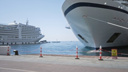 Defocused cruise ship harbor scene at a quay with moored vessels, bollards and safety posts, soft...