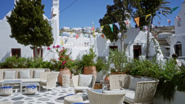 Sunlit mediterranean courtyard with wicker seating and potted plants, softly blurred bokeh background, cafe; background backdrop copyspace calm. - Powered by Adobe