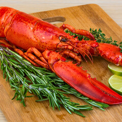 Delicious cooked lobster with fresh herbs and lime on a wooden board