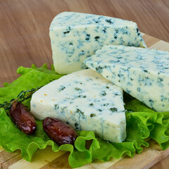 Gourmet blue cheese wedges with dates and lettuce on a wooden board