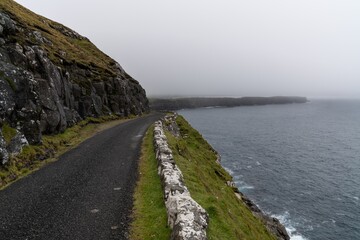 narrow single-lane road leading along steep cliffs from Sanduk to Soltavik on the Faroese Island of Sandoy