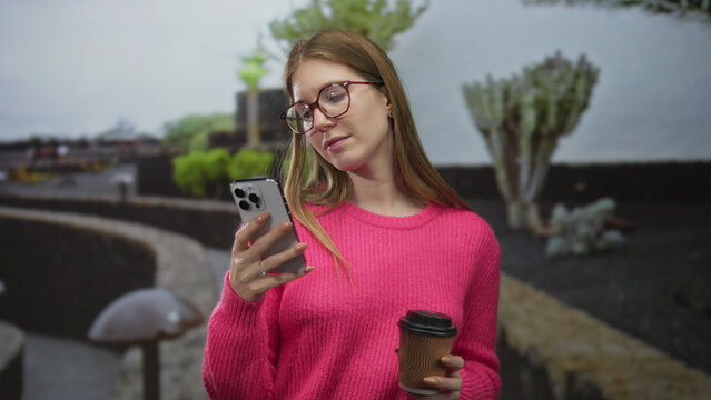 Woman holding smartphone and coffee cup by curved stone wall in park; digital lifestyle calm routine. - Powered by Adobe