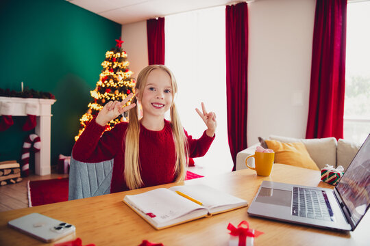 Joyful Christmas moment at home with a smiling girl by the tree and laptop enjoying cozy holiday vibes and festive decorations creating a warm family scene