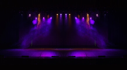 An empty stage of the theater, lit by spotlights and smoke before the performance