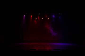 An empty stage of the theater, lit by spotlights and smoke before the performance