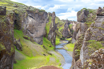 Stunning Icelandic landscape showcases a verdant canyon and a winding river under a cloudy sky