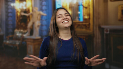 Woman smiling in a museum setting with art and golden decor, exuding joy and warmth in an indoor...