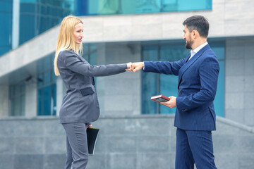 Business professionals exchanging a fist bump outside a modern building during the day
