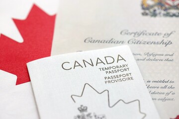 Canadian temporary passport and certificate of citizenship lies on flag close up
