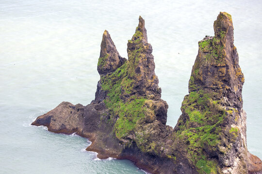 Majestic sea stacks rise above the calm waters in Vik, Iceland during a clear day