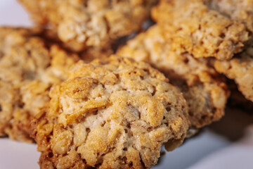 Close-up of freshly baked, golden brown oatmeal cookies on a white surface. Crispy texture and visible oats.