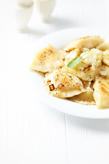 Dumplings with potato and cottage cheese stuffing (pierogi). Wooden background. Copy space.	