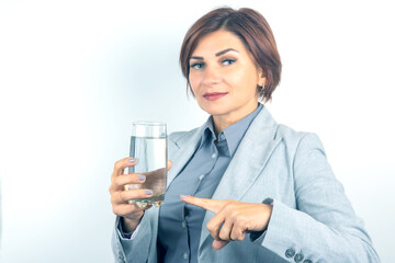 Woman in business attire holding a glass of water while gesturing in a modern environment