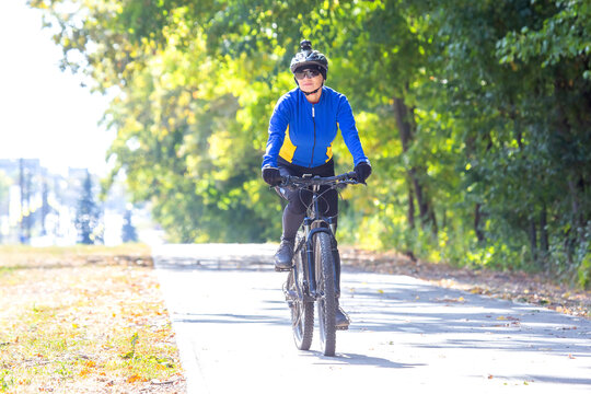 Cyclist on a sunny day riding along a tree-lined path in autumn