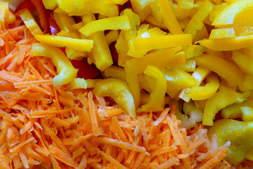 Colorful mix of sliced yellow peppers and grated carrots on a kitchen counter