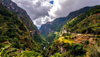 Naklejka premium Majestic vista of a deep, verdant canyon under a dramatic sky. Winding river carves path through the mountainous terrain. Clouds cast shadows