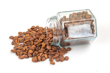 Brown coffee beans spilling from a glass jar on a white background