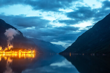 Evening glow over the tranquil fjord in Norway near the mountains and reflected clouds