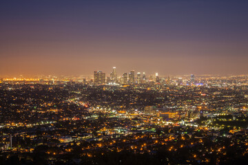 Panoramic night view of Los Angeles city from Griffith Observatory, glowing skyline, urban lights, cityscape under twilight sky, vibrant atmosphere, modern architecture, travel destination, California
