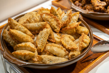Golden fried dumplings fill a rustic ceramic dish, inviting as a savory appetizer or snack.