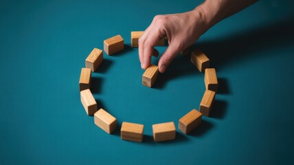 Hand placing wooden block to complete clock face on blue background