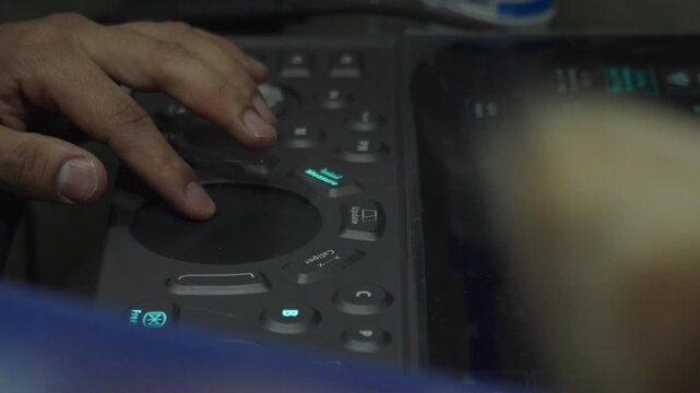 Veterinarian hands operating an ultrasound machine console