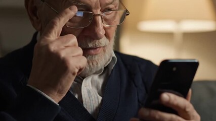 Close-up of senior man adjusting glasses while using smartphone - Powered by Adobe