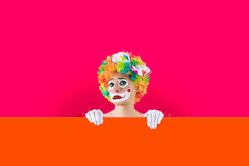 Whiny female clown peeking out from behind sign blank template mock up for advertising, posters, greetings, invitations. Entertainer as Joker in a suit and wig, with clown whiteface makeup.