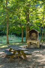 Wooden picnic table and stone barbecue in Umbria forest