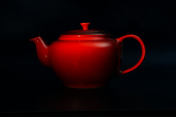 Red tea pot with black background. 