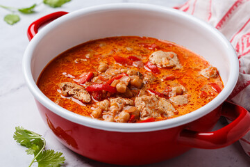 Tikka masala with chicken and chickpeas in red pot.