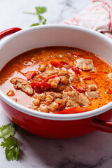 Tikka masala with chicken and chickpeas in red pot.