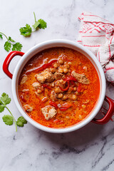 Tikka masala with chicken and chickpeas in red pot.