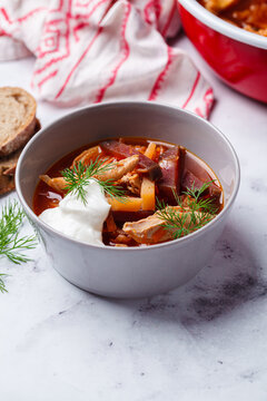 Classic homemade borscht with chicken in a grey bowl.