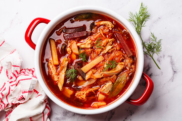 Classic borscht with chicken in a red pot.