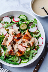 Salad with grilled salmon, cucumber, radish, capers and tahini dressing.