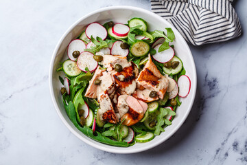 Salad with grilled salmon, cucumber, radish, capers and tahini dressing.
