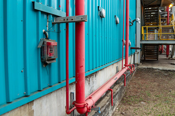 Industrial scene showing blue corrugated metal wall and red fire suppression pipes system.