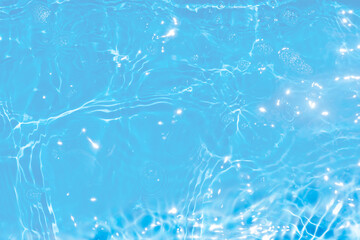 Blue water with ripples on the surface. Defocus blurred transparent blue colored clear calm water surface texture with splashes and bubbles. Water waves with shining pattern texture background.