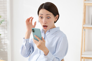 スマホを持って驚く女性