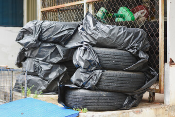 Stacked tires covered in black plastic near a chain-link fence.