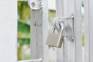 Padlock securing a silver metal gate with a blurred background.