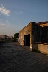Fototapeta premium Abandoned stone structure with graffiti and dark doorway at sunset
