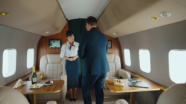 Successful businessman in an elegant suit boarding a first-class private jet, greeted by a smiling flight attendant before taking his comfortable seat for a luxurious business travel experience
