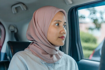 Asian Muslim woman traveler sitting in car back seat