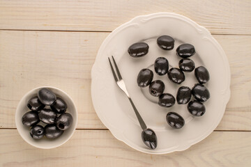 Canned black pitted olives on a wooden table, top view.