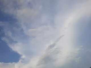 A soft rainbow appears in a cloudy sky