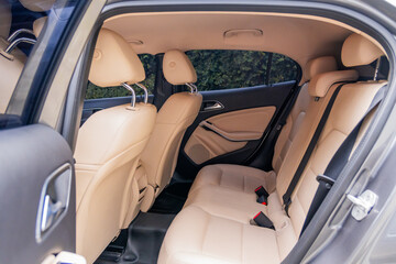 Photograph showing the interior of a modern vehicle from the rear with beige leather seats