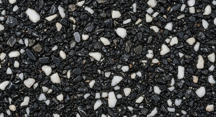 Wet black asphalt texture with white and grey stones. Abstract macro background of a dark aggregate surface. Construction material pattern